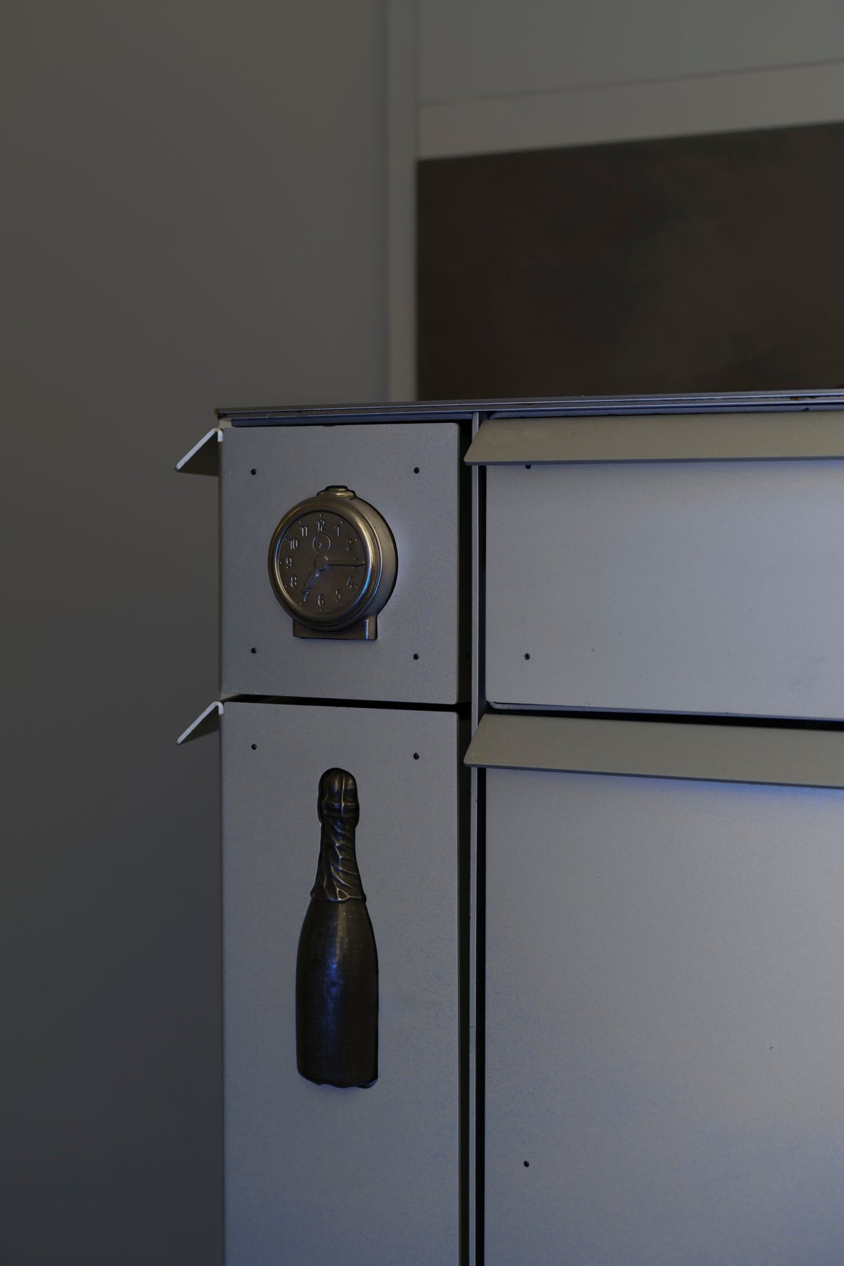 Swing out drawers with a tin clock and champagne-bottle ornament above the anodised aluminium drawer fronts